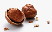 Two hazelnuts on a white surface