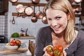 Junge Frau mit Tomaten in den Händen zwinkert in die Kamera