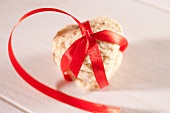 A heart-shaped biscuit tied with a red ribbon