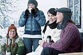 Junge Leute trinken warmen Tee vor einer Hütte