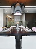 Designer hanging lamp with a black shade over a set dining table