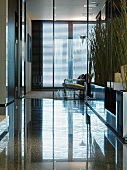 Lobby with a highly polished stone floor and view through a glass wall partition of armchairs