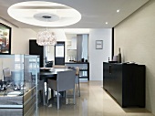 Dining area with designer lamp hanging from a recessed opening in a suspended ceiling in a modern living room