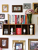 Small book shelf surrounded by framed photographs