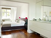 Modern washstand in ensuite bathroom and view of bed through open doorway