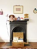 Basket with open lid in front of black fireplace with toys on mantelpiece