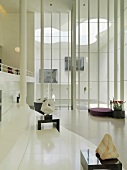 Zeitgenössische Skulpturen in einer Lobby mit Blick durch raumhohe Fenster auf den modern gestalteten Innenhof