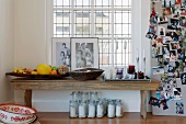 Fruit bowls, salt shakers and table decorations on an old wooden bench next to a wall covered with photos