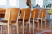 Moderne, schlichte Holzstühle am Esstisch auf einem bunten Teppich