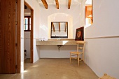 Blick auf den Steinwaschtisch eines gemütlichen, hellen Badezimmers mit Holzbalkendecke