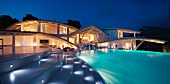 Modern home with illuminated steps and swimming pool at dusk pano