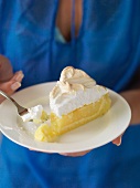 A woman holding a plate of lemon meringue pie