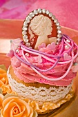 A cupcake decorated with buttercream and a Marie Antoinette pendant