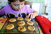Young boy choosing a cookie from the baking rack