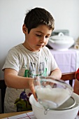 Young boy sifting flour into a bowl