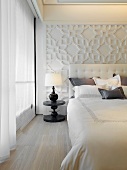 Klassisch modernes Schlafzimmer mit Bett vor reliefartig gestalteter Wand