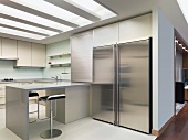 Grosser Edelstahlkühlschrank in moderner Einbauküche mit Frühstückstheke und indirektem Licht von oben