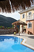 Hanging chair and parasol next to swimming pool on terrace (Villa Octavius, Lefkas, Greece)