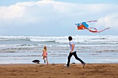 Vater und Tochter lassen am Strand Drachen steigen