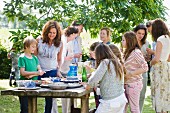 Erwachsene und Kinder stehen am Buffet bei einem Gartenfest