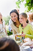 A mother and daughter standing by the buffet at a garden party