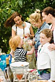 Kinder und Erwachsene stehem am Buffet bei einem Gartenfest