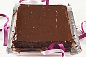 A square chocolate cake on a piece of silver foil