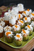Various types of vegetable puree in glasses topped with whipped cream