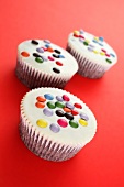 White cupcakes decorated with coloured chocolate beans