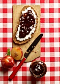 A slice of rustic bread topped with cream cheese and plum jam