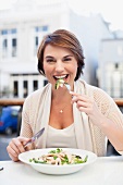 Frau isst Salat in einem Bistro