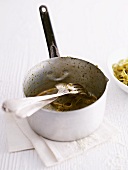 The remains of pasta and pesto in a pot
