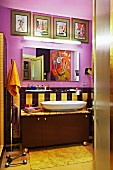 Cheerful bathroom in warm shades with collection of artworks and large painting reflecting in mirror