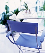 Modern folding chair upholstered in blue in front of a simple table