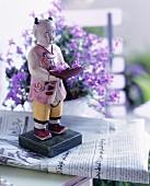 Painted, Asian wooden figure standing on a newspaper