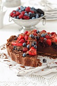 A chocolate cake topped with berries, sliced