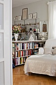 Half-height bookcase as partition next to chaise longue with white cover
