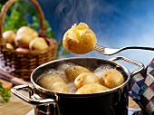New potatoes in a pot of boiling water and on a fork