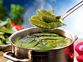 Mange tout being added to a pot of boiling water