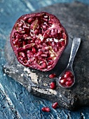 Half a pomegranate with a spoonful of seeds next to it