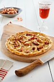 Flammkuchen mit Speck auf Holzbrett mit Rotwein