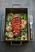 Roast cochon de lait with apples and green beans in a roasting tin