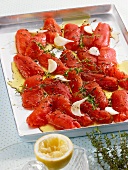 Tomatoes on a baking tray with thyme, garlic and olive oil