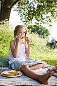 Mädchen isst Ananas auf einer Picknickdecke