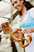 Junge Frau mit einer Mass Bier und Brezel