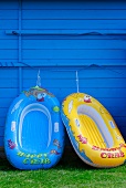 Two rubber dinghies on a blue wooden wall