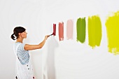 Woman painting colour swatches on wall