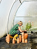 Junge Frau beim Einpflanzen von Blumen im Gewächshaus