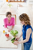 Two woman preparing salad in kitchen