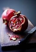 A pomegranate which has been broken open on a wooden board